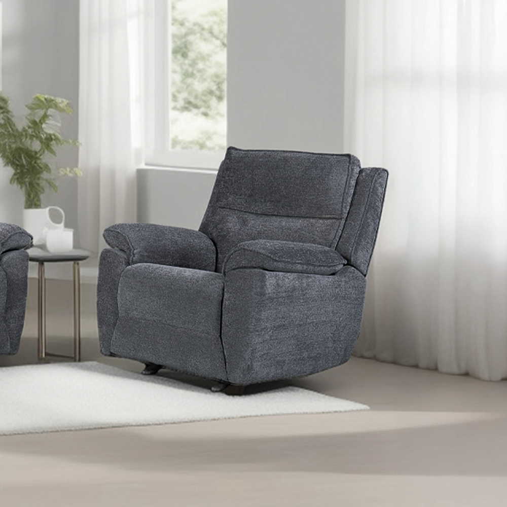 A dark grey recliner chair with armrests, upholstered in chenille fabric, positioned in a cozy living room setting next to a white round side table with a white lamp.