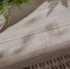 Close-up of a wooden surface with a plant in the corner