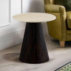 Wooden side table with a textured dark base in a room with a green armchair.
