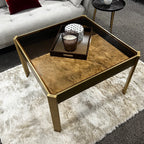 Brown coffee table with gold frame on a white rug