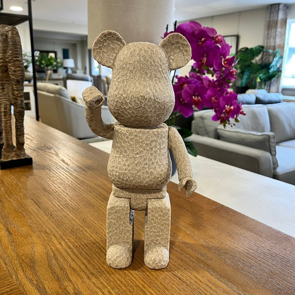 Textured bear figurine on a wooden table with a living room in the background