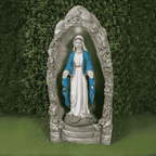A statue of the Virgin Mary standing in a grotto setting, with a blue and white robe, placed in a garden environment.