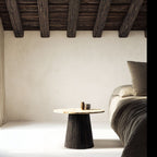 Minimalist bedroom with a bed, side table, and wooden ceiling beams.