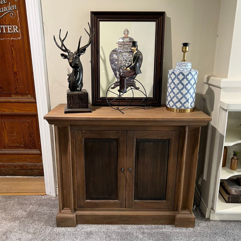 Wooden cabinet with decorative items including a lamp, sculpture, and framed picture.