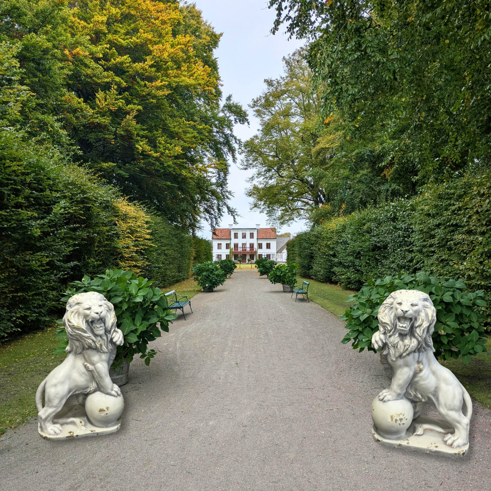 Pathway flanked by lion statues with a house in the background
