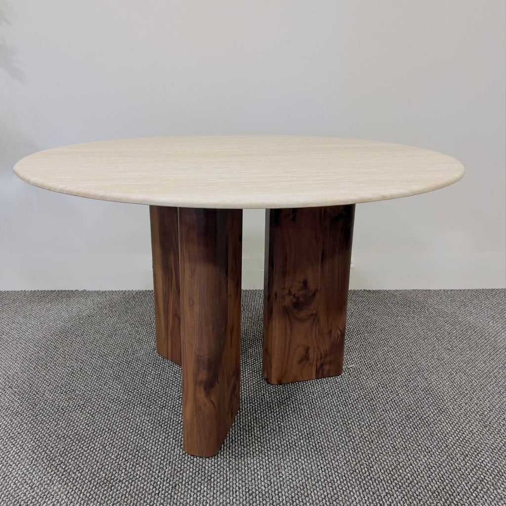 Round wooden table with a light-colored top on a gray carpeted floor.