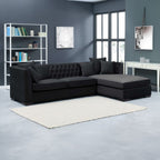 Black sectional sofa in a modern living room with gray walls and a white rug.